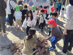 トラックの芋山から、芋を降ろす子どもたち。