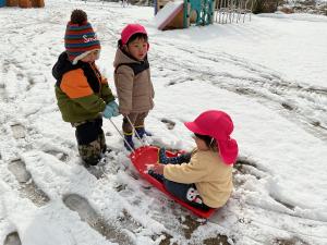 そり遊びをする1歳児
